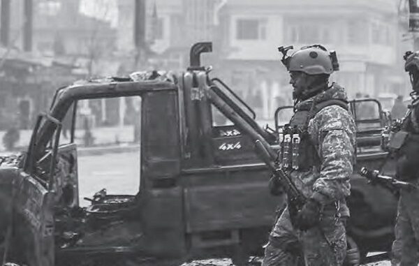 Afghan security force members walk past a bombed truck in Kabul (AFP photo by Zakeria Hashimi)